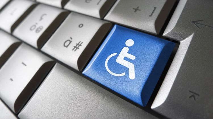 Photograph of a keyboard with symbols. One of the keys is blue, and has the icon of a person in a wheelchair.