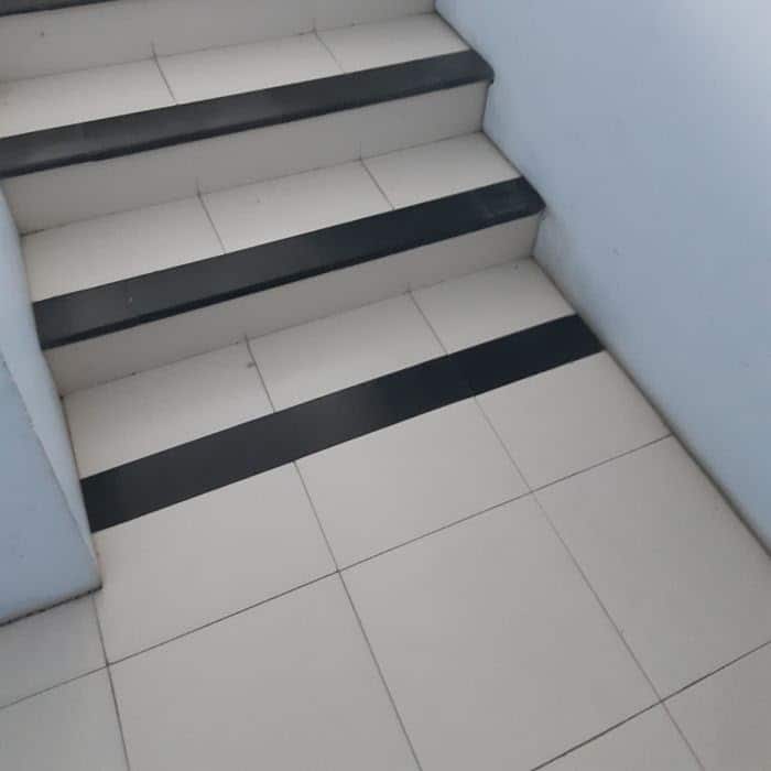 Photograph of a white staircase where the edges of each step are painted black. There is a black "edge" painted at the bottom of the staircase as well, giving the issulsion of a step, where there is none.