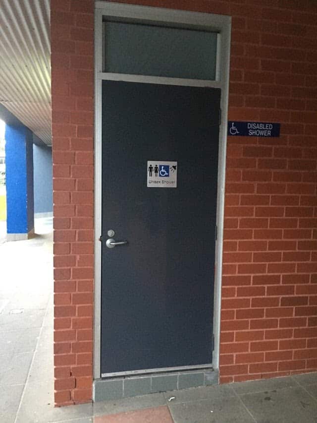 Photograph of the entrance to a unisex and disabled-friendly shower. The entrance to the shower has a raised step without a ramp.