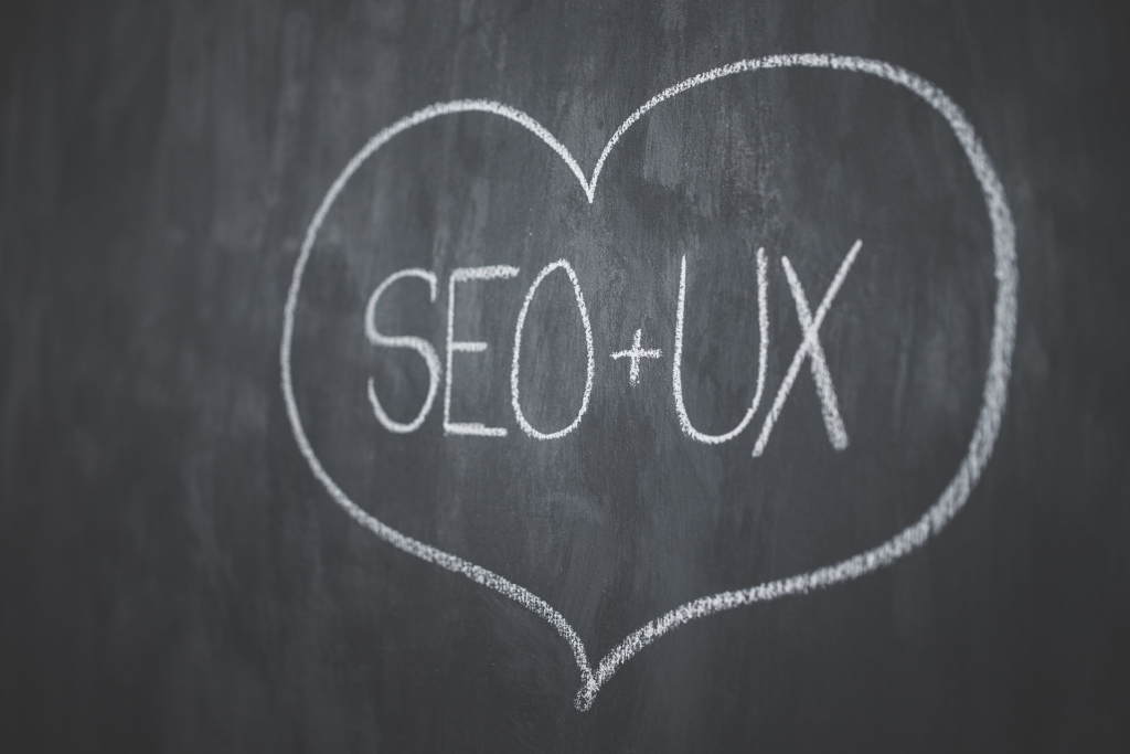 Photograph of a chalkboard with a drawing of a heart shape. Inside the heart are the words "SEO + UX"