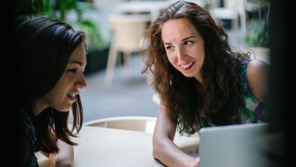 Two women talking while looking into a laptop