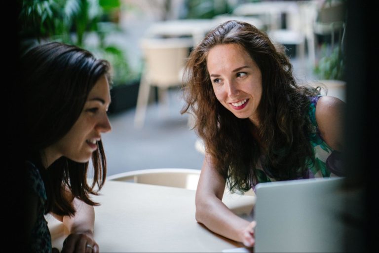 Two women talking while looking into a laptop